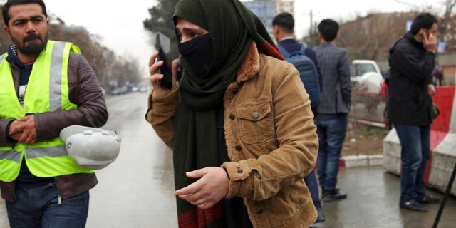 A woman talks to her phone as her relative was at the site of a suicide bombing in the diplomatic area of capital Kabul, Afghanistan