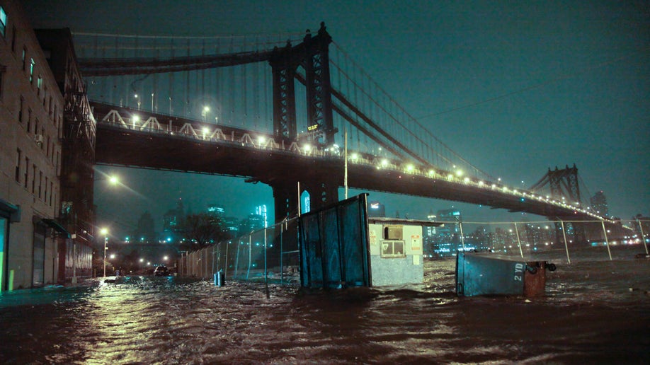 Streets are flooded under the Manhattan Bridge in the Dumbo section of Brooklyn, N.Y., Monday, Oct. 29, 2012. Sandy continued on its path Monday, as the storm forced the shutdown of mass transit, schools and financial markets, sending coastal residents fleeing, and threatening a dangerous mix of high winds and soaking rain. (AP Photo/Bebeto Matthews)