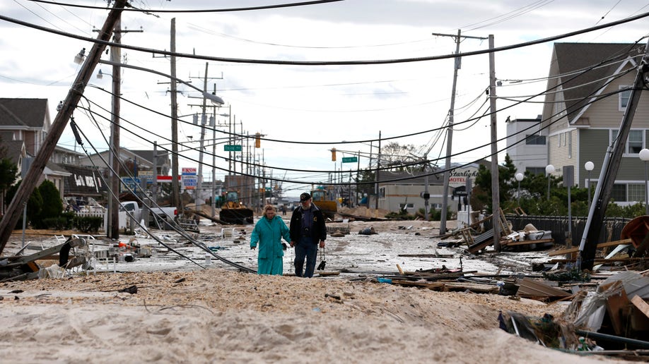 Robert Bryce, right, walkswith his wife, Marcia Bryce, through destruction from superstorm Sandy on Route 35 in Seaside Heights, N.J., Wednesday, Oct. 31, 2012. Sandy, the storm that made landfall Monday, caused multiple fatalities, halted mass transit and cut power to more than 6 million homes and businesses. (AP Photo/Julio Cortez)