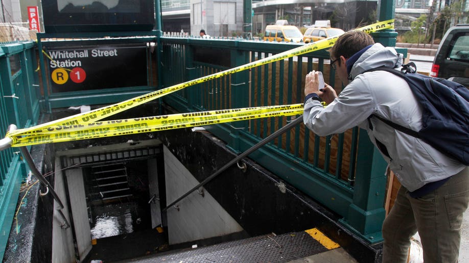 A man uses his mobile phone to photograph a closed and flooded subway station in lower Manhattan, in New York, Tuesday, Oct. 30, 2012. Due to superstorm Sandy, New York City awakened Tuesday to a flooded subway system, shuttered financial markets and hundreds of thousands of people without power a day after a wall of seawater and high winds slammed into the city, destroying buildings and flooding tunnels. (AP Photo/Richard Drew)