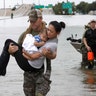Houston Police SWAT officer Daryl Hudeck carries Catherine Pham and her son Aiden from floodwaters, Sunday, in Houston