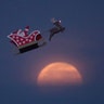 A 10-foot long remote controlled flying Santa makes a test flight past a setting moon over the ocean in Carlsbad, California, December 3