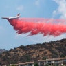 A DC-10 Tanker drops Phos-Chek retardant across a ridge while fighting the 