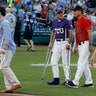 Injured aide Zach Barth, left, and Rep. Roger Williams, R-Texas, also on crutches walk off the field before the Congressional baseball game 