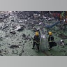 Firefighters stand amid debris in a childrens playground near the tower block on fire, in north Kensington, West London