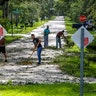Neighbors help each other clear their road of debris in Kissimmee, Fla., Monday