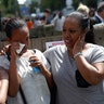 A woman is comforted as they stand near the destroyed apartment building in London