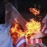 Palestinians burn a poster of U.S. President Donald Trump and a representation of an American flag, during a protest in Gaza City, December 7