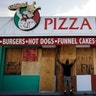 Ryan Otway boards up a pizza place along the boardwalk in Daytona Beach, Fla., Thursday