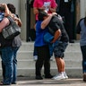 People embrace outside the Alamo Gym where students and parents reunited following a shooting at Santa Fe High School, May 18, 2018