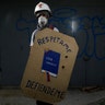 A demonstrator holding a shield that depicts the Venezuelan Constitution and reads 