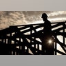 A construction worker climbs onto a roof at sunrise to avoid the heat in Phoenix, Tuesday