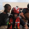 Senior Airman John J. Kosequat and Staff Sgt. Ryan R. Dush carry a child and dog off an HH-60 Pave Hawk helicopter