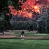 The Eagle Creek wildfire burns as golfers play at the Beacon Rock Golf Course in North Bonneville, Washington, September 4