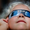 Piper Truza watches a phase of a partial solar eclipse visible in Detroit