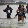 A man wades through flood waters from Tropical Storm Harvey while helping evacuate a boy in east Houston, Texas, Monday