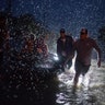 People help push a boat with evacuees to high ground along Tidwell Road in east Houston, Monday