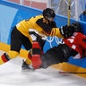 Felix Schutz of Germany hits Maxim Noreau of Canada, into the boards in their ice hockey semi-final match at the Winter Olympics
