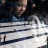 A woman is seen behind a window as she watches men's curling matches at the 2018 Winter Olympics