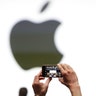 An audience member takes a photo of the Apple logo before the start of the company's annual developer conference