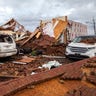 Ren retrieves clothing from a damaged car parked at a home that was hit by a tornado, Sunday, Jan. 22, 2017, in Adel, Ga.