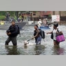 People walk through water to a staging area to evacuate from flood waters from Hurricane Harvey in Dickinson, Texas, Sunday