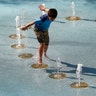 A child uses the CityScape splash pad to stay cool as temperatures climb to near-record highs in Phoenix, Tuesday