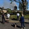 People look at smoke billowing from the apartment tower on fire, in West London
