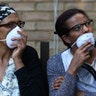 People wear masks near the apartment building fire, in West London
