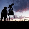 A woman looks through a telescope on the football field at Madras High School in Madras, Oregon, August 20