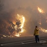 A firefighter covers his eyes as he walks past a burning hillside in Santa Rosa