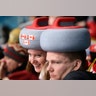 Spectators sport headwear shaped as curling stones as they watch the mixed doubles curling finals match at the 2018 Winter Olympics