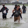 A man wades through flood waters from Tropical Storm Harvey while helping evacuate a boy in Houston, Texas, August 28, 2017