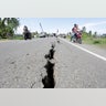 Motorcyclists pass a damaged section of a road following an earthquake in Meuredu, Pidie Jaya, in the northern province of Aceh, Indonesia.