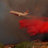 A DC-10 aircraft drops fire retardant on a wind-driven wildfire in Orange, California. At least 11 people have died in the fire October 9, 2017