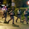 Police run to cover at the scene of a shooting near the Mandalay Bay resort and casino on the Las Vegas Strip, Sunday