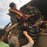 An Iraqi Medic and civilians lift an elderly lady in a wheelchair into the back of a transport truck, May 5, 2017