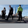 Commuters walk past a City of London police officer standing on London Bridge after is was reopened