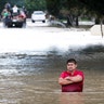 A man stands in deep flood water along West Little York Road in Houston, Tuesday
