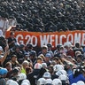 German riot police stand in front of protesters during demonstrations at the G-20 summit in Hamburg, Germany, July 6