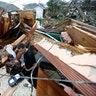 Gregory Rugon looks for his glasses at the spot where he took cover in his home after the tornado.