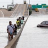 Evacuees wade down a flooded section of Interstate 610 as floodwaters from Tropical Storm Harvey rise in Houston, August 27, 2017