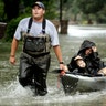 People evacuate a neighborhood in west Houston inundated by floodwaters from Tropical Storm Harvey on Monday