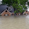 A home is surrounded by floodwaters from Tropical Storm Harvey, Monday, in Spring, Texas