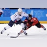 Jocelyne Lamoureux-Davidson of the United States and Marie-Philip Poulin of Canada compete for the puck at the Winter Olympics