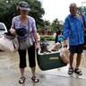 Evacuees carry their dogs into the the George R. Brown Convention Center after being rescued from flooding, in Houston, Sunday