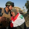 A member of Iraqi Federal police kisses an old woman in West Mosul, Iraq July 9