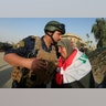 A member of Iraqi Federal police kisses an old woman in West Mosul, Iraq July 9