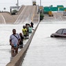 Evacuees wade down a flooded section of Interstate 610 as floodwaters from Tropical Storm Harvey rise Sunday in Houston