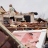 Jeff Bullard sits in what used to be the foyer of his home as his daughter, Jenny Bullard, looks through debris at their home that was damaged by a tornado.